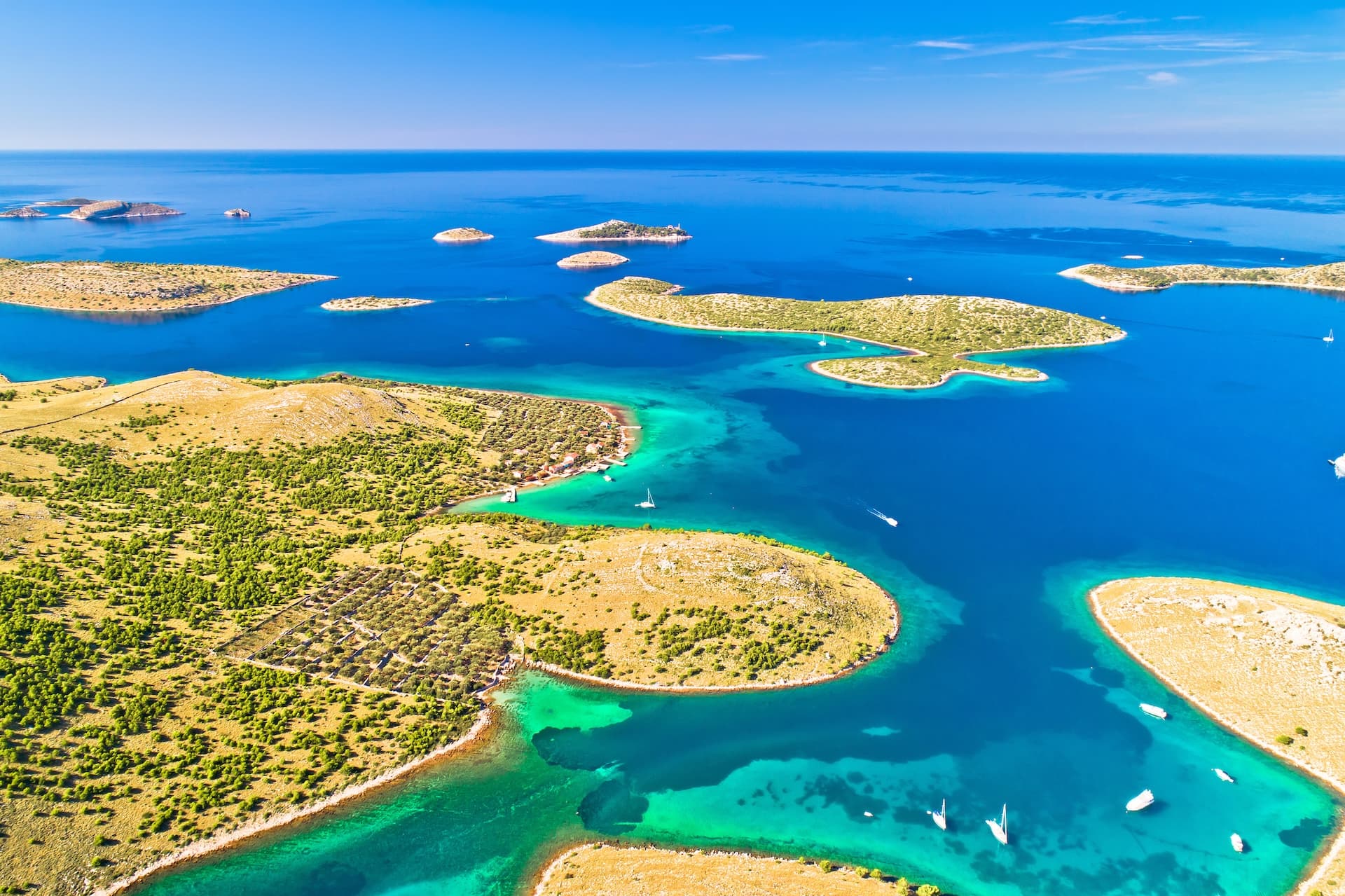 Aerial view of Kornati islands with turquoise coves and sailboats on deep blue Adriatic Sea.