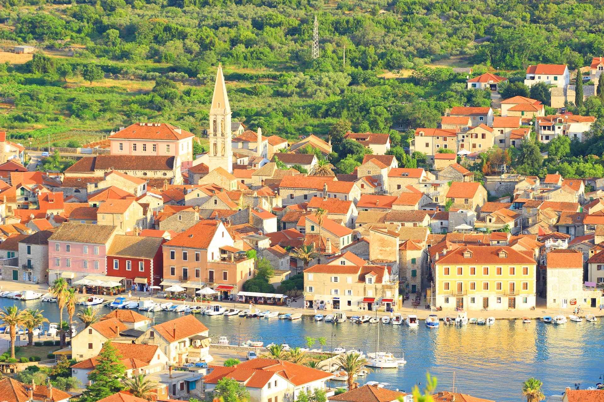 Town marina in Stari Grad, Hvar, with terracotta roofs and a tall church spire.