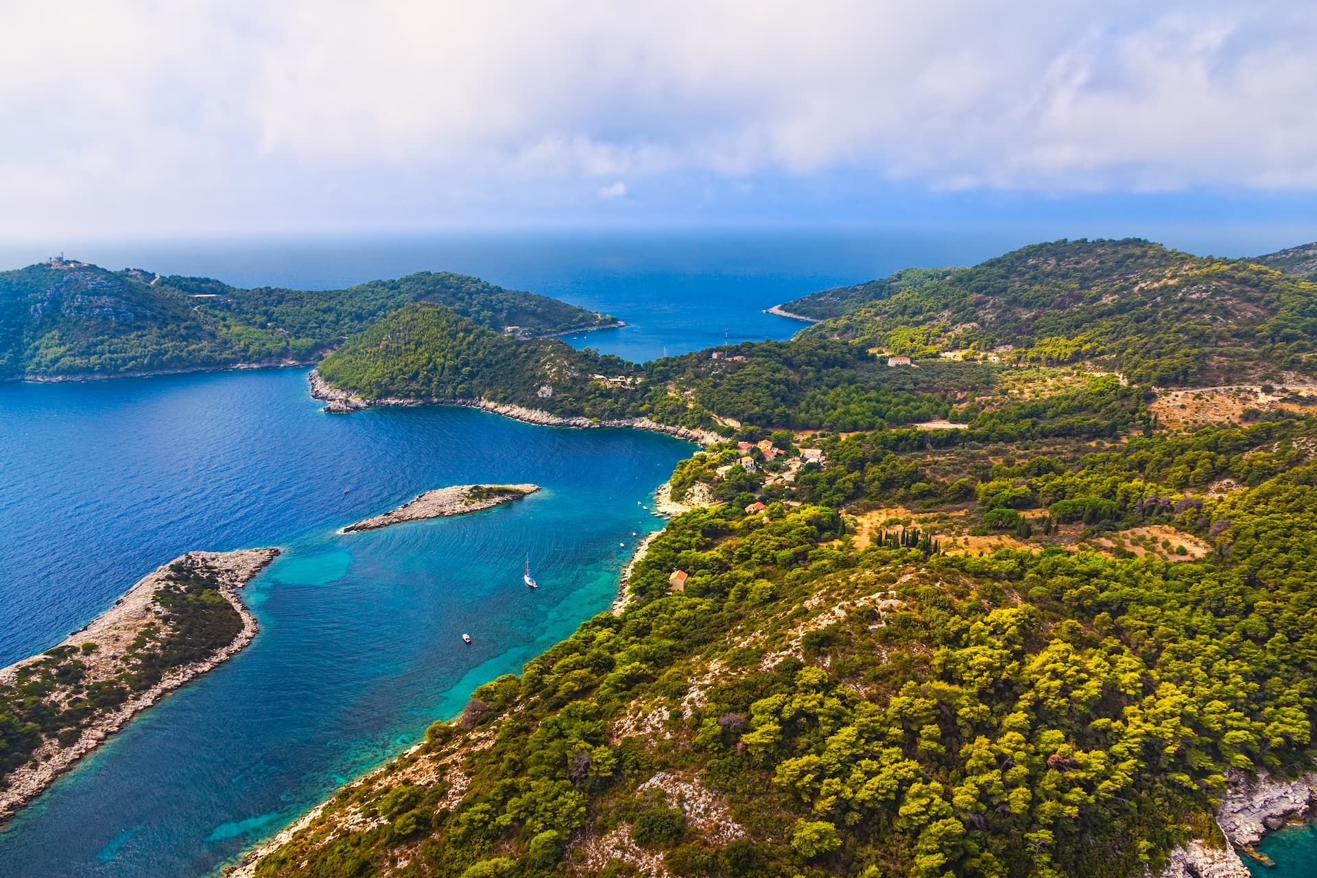Aerial view of Mljet Islands with lush green hills meeting turquoise Adriatic Sea waters.