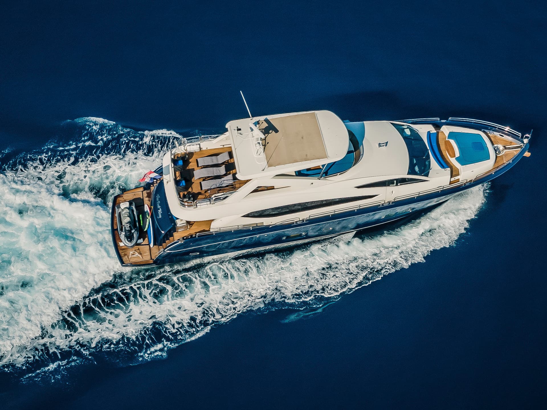 Luxury yacht speeding across deep blue water leaving white wake behind
