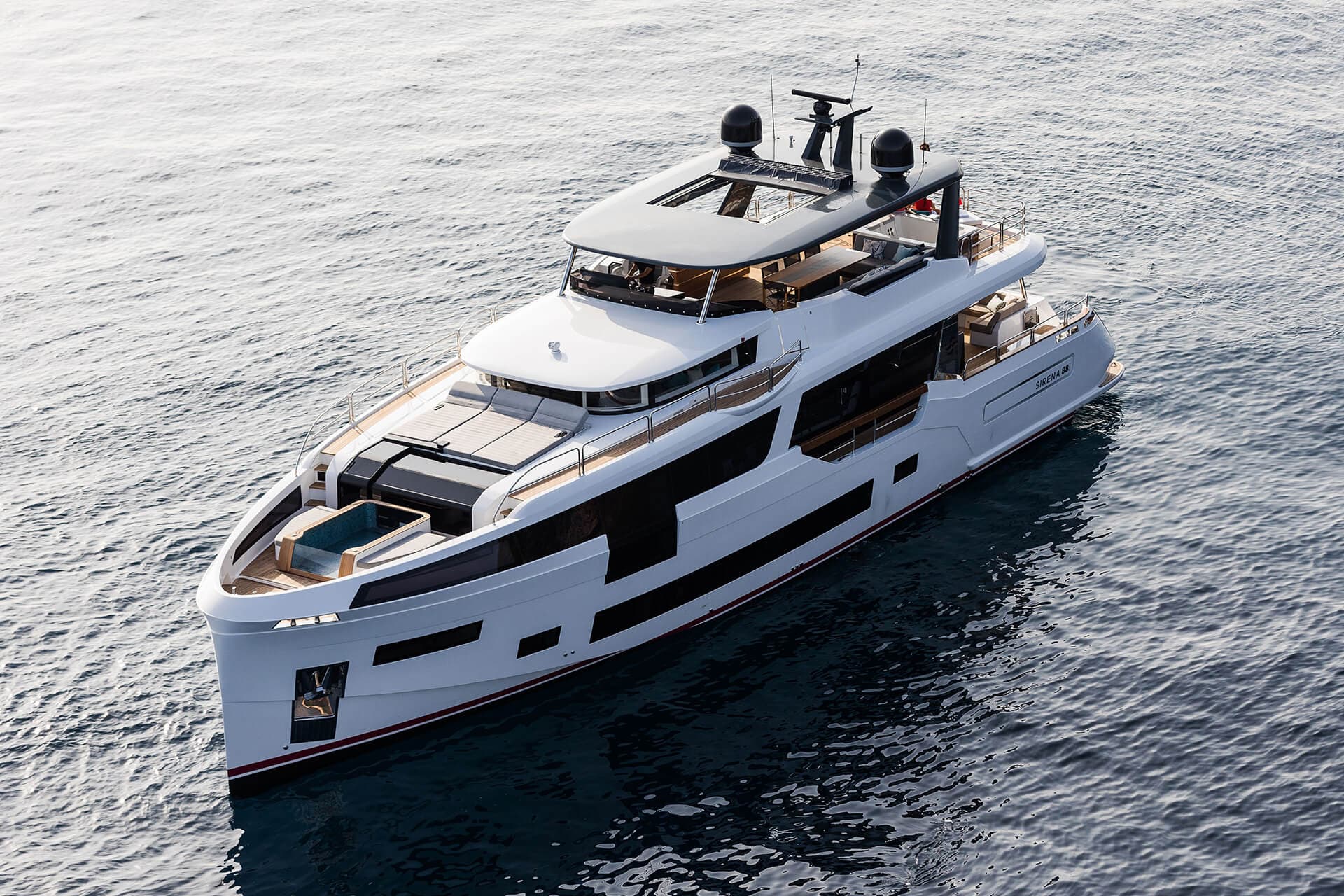White luxury motor yacht named Sirena 68 cruising on dark blue coastal waters.