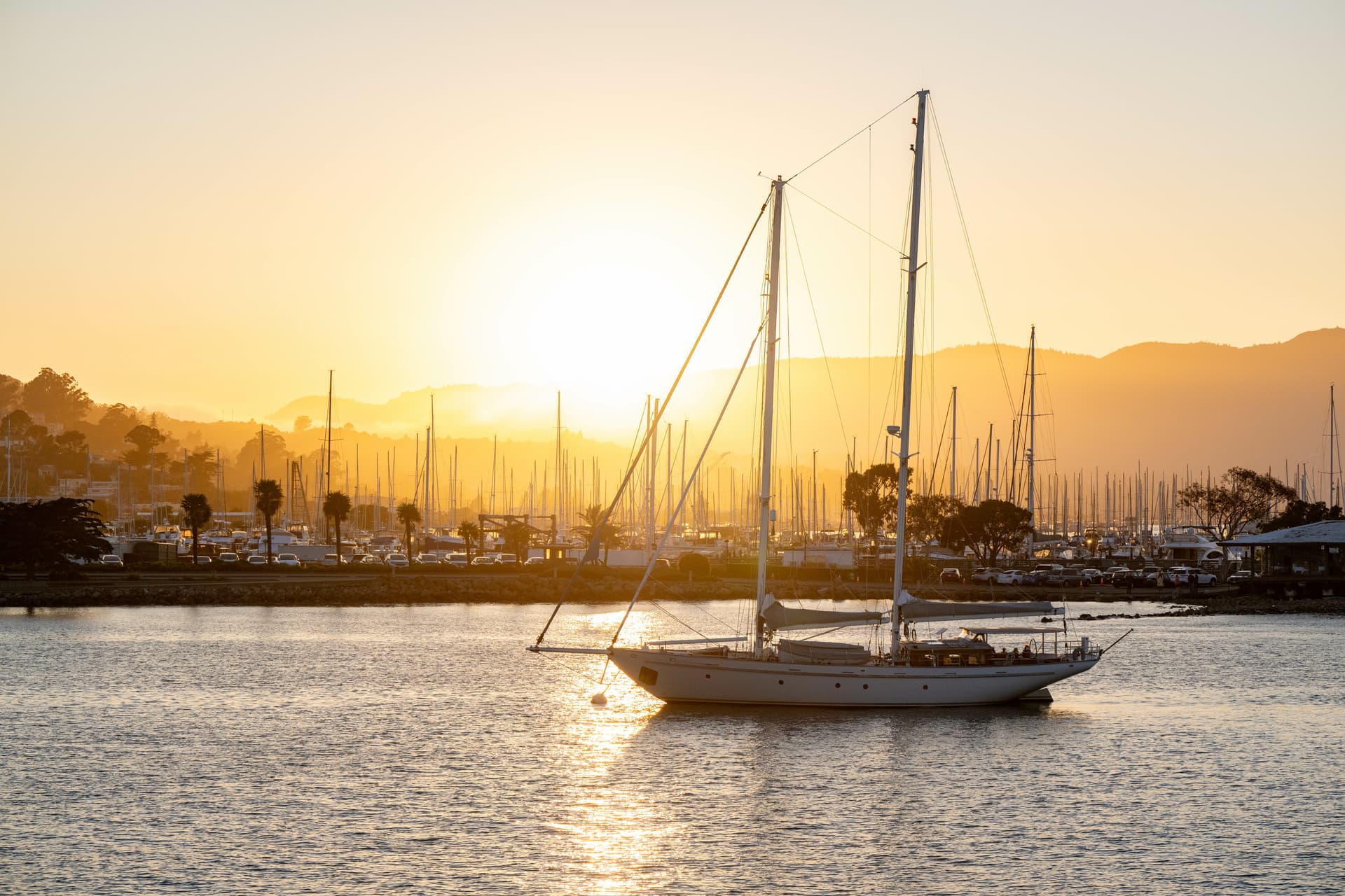 Sailboat on water at sunset with marina and hills in background, Croatia.